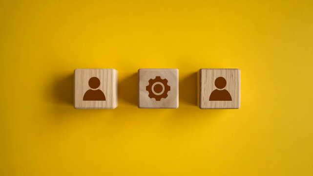 Three wooden blocks with human and gear icons on a yellow background representing teamwork and machinery  business concept