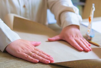Obraz premium Woman Wrapping Package in Brown Kraft Paper at Wooden Table