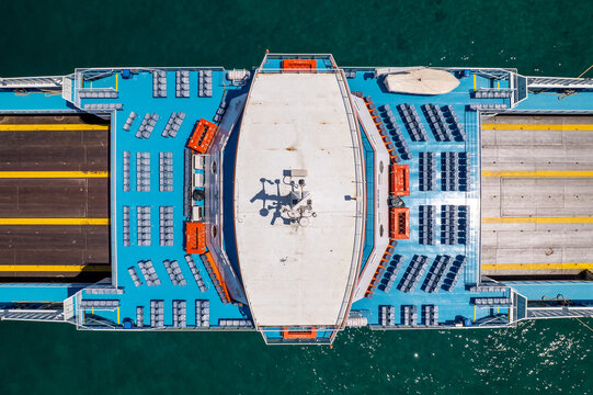 Ferry boat deck with passenger seating and car lanes, aerial drone view