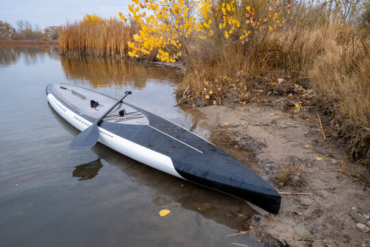 stand up paddleboard with paddle on a calm lake in fall scenery