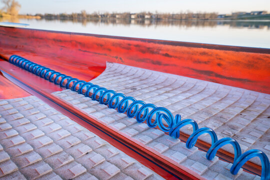 Deck of a racing stand up paddleboard with a safety leash on a calm lake