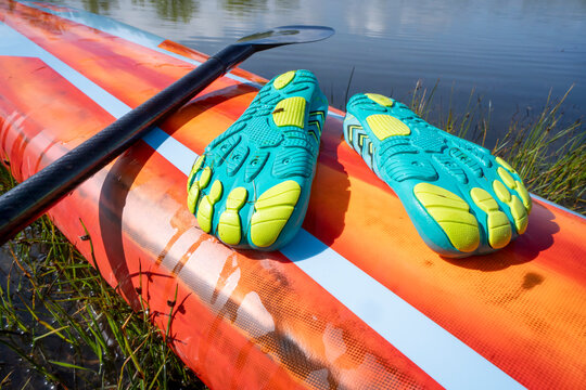 lightweight low-profile water shoes (soles up) for kayaking and other wet sports on a deck of a stand up paddleboard