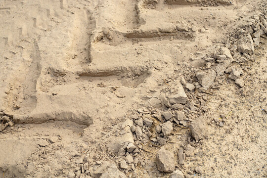 Tire track texture and sand background from big wheel, angle view of tractor tread mark on dry soil with loose dirt clods