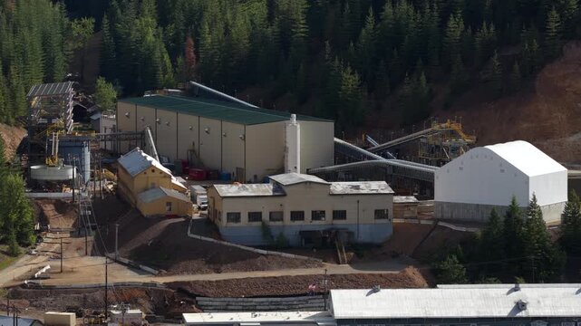 Aerial of industrial complex near Kellogg Idaho showing large buildings and construction activity surrounded by dense forest in spring