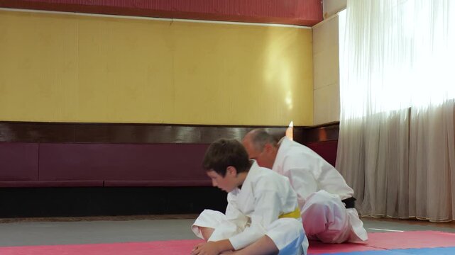 A trainer and a young athlete perform warm-up exercises while sitting