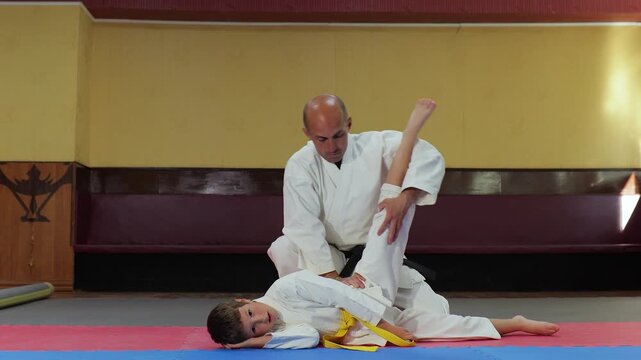 A trainer helps a young athlete perform leg stretching exercises
