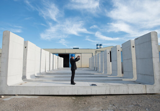 Boss in cement company takes photograph of concrete structures ready for distribution and intended for prefabricated construction. Cordoba, Spain.