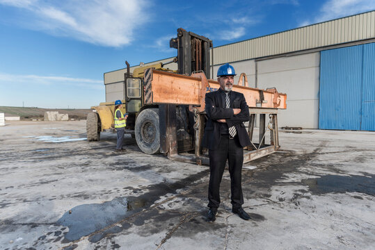  Construction senior boss in outdoors image near to bulldozer and work woman, Cordoba, Spain.
