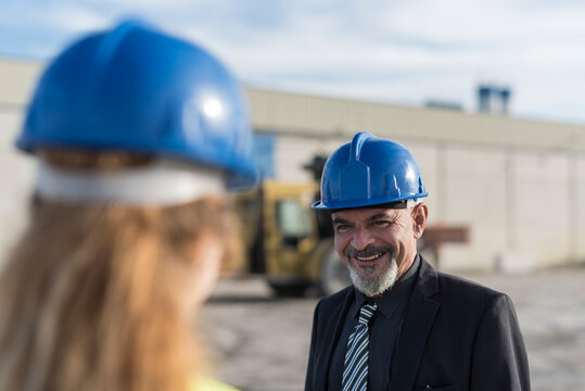 Senior boss talking to young female worker at concrete factory outdoors. Cordoba, Spain.