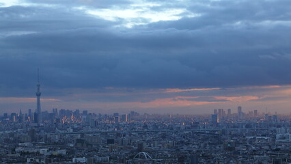 Fototapeta premium 夕陽に照らされた都市の風景 雨雲が残る空に広がる幻想的な光景 / Cityscape Illuminated by Sunset Beneath Rain Clouds in a Dramatic Evening Sky