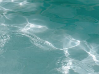 Fototapeta premium Close-up of shimmering turquoise water surface with gentle ripples and sunlight reflections, creating abstract patterns