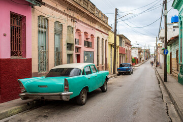 Obraz premium Turquoise vintage car on a colorful colonial street in Cuba.