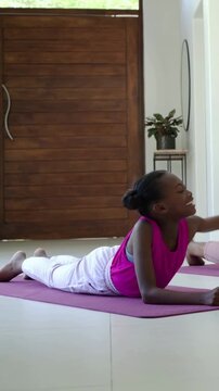 Vertical video: Turning toward other, girl doing cobra on pink mat entry pink top, copy space