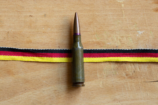 Cartridge on the background of a ribbon in the colors of the German flag on a wooden board on the theme of defense, army, military service