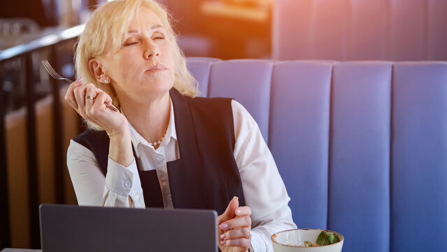 Caucasian Elderly Businesswoman Closing Eyes And Tilting Head Back During Lunch Break, Breathing Deeply In Sunlit Cafe, Serene Expression, Moment Of Stress Relief And Mental Reset Between Meetings.