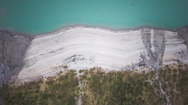 Aerial drone shot of turquoise alpine lake surrounded by steep cliffs