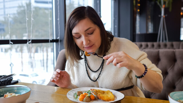 Woman Sampling Meal. Female Enjoying Food At Cafe. Woman In Casual Diner Savoring Plated Culinary Creation. Female Diner Carefully Tasting And Appreciating Flavors In Modern Cafe Environment