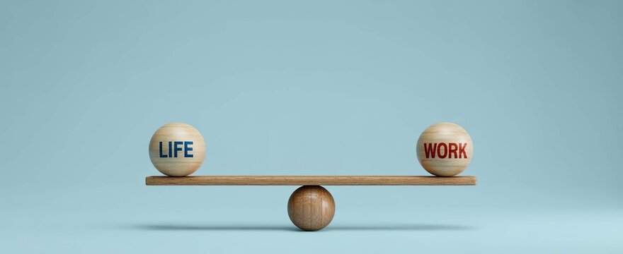 Wooden balls with L I F E and W O R K text on a balance scale