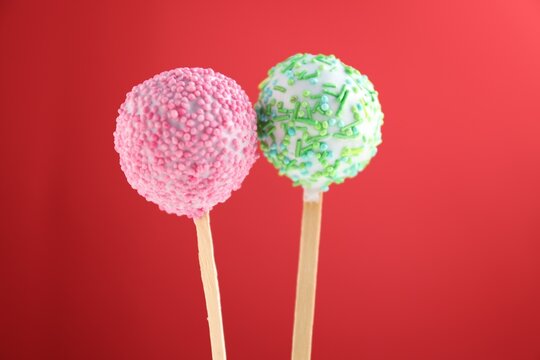 Tasty cake pops on red background, closeup