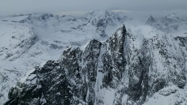 Aerial view of jagged snow mountain ridge under overcast sky
