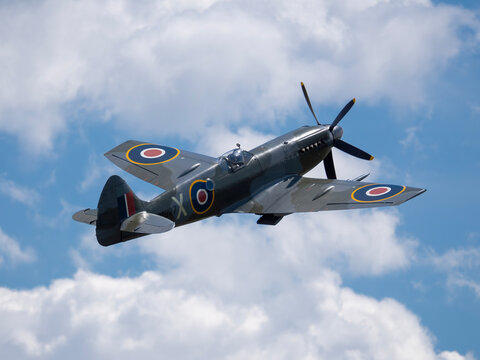 MLADA BOLESLAV, CZECH REPUBLIC - JUNE 13, 2026: A historic Supermarine Spitfire Mk XIV (registration RM927) fighter aircraft climbing into a blue, cloudy sky during an airshow display.