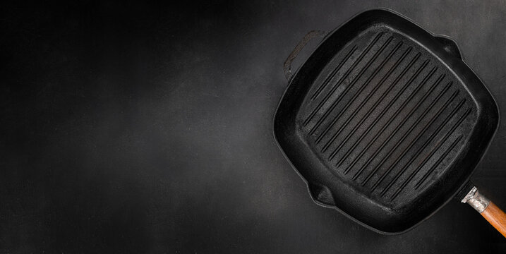 Empty cast iron grill pan on dark background with copy space