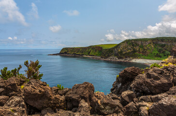 Obraz premium Dramatic volcanic cliffs at Alagoa Viewpoint overlooking the deep blue Atlantic Ocean on Terceira Island, Azores, Portugal, showcasing rugged lava coast scenery and natural beauty
