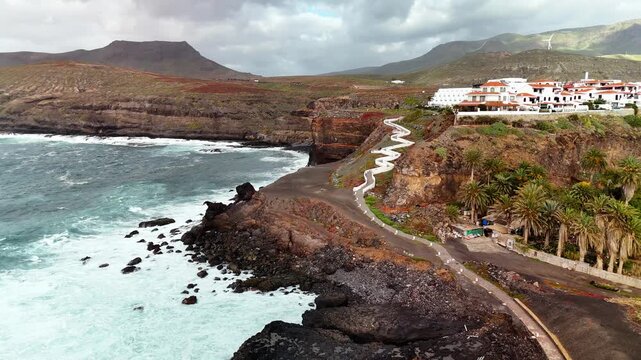 Aerial drone flight towards coastal path and houses, El Turman, Agaete, Gran Canaria