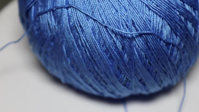 A ball of blue yarn sits on a table, ready for use in crafting or knitting