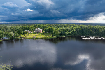Fototapeta premium Birini Castle and Lake Birini beneath an approaching summer thunderstorm, aerial view of Latvia