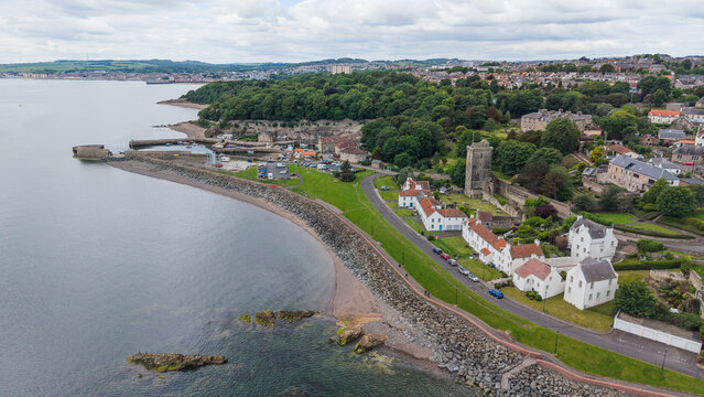 Panoramic view of Dysart historic coastal village with traditional architecture, St Serf's Tower, and the rocky shoreline of the Firth of Forth in Fife, Scotland.