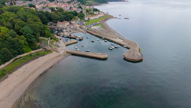 High aerial view of historic Dysart Harbour surrounded by green nature, rocky beach, and the scenic coastline of Fife, Scotland