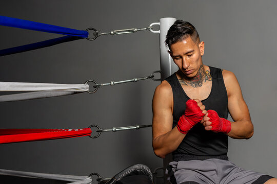 Young Hispanic boxer checking hand wraps and clenching fists before training