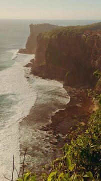 Vertical video. Slow Motion View Of Karang Boma Cliff And Rolling Ocean Waves During Golden Hour, Coastal Beauty And Travel Destination