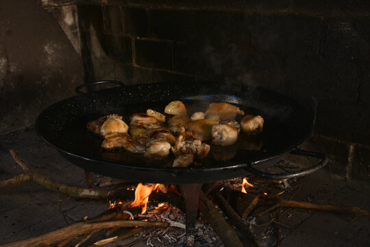 Meat browning in paellera over wood fire