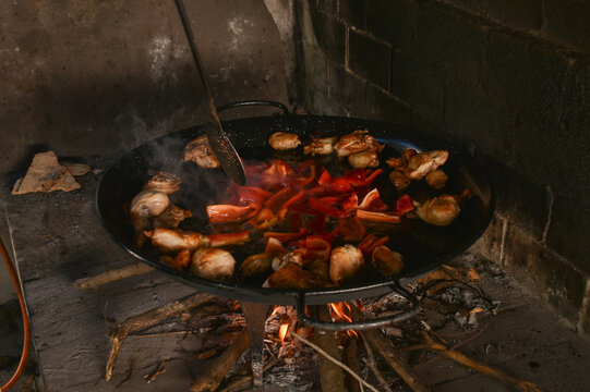 Close up of paellera with chicken and peppers in wood fired oven