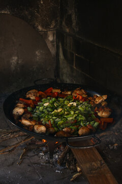 Traditional Valencian paella cooking over wood fire with meat and vegetables