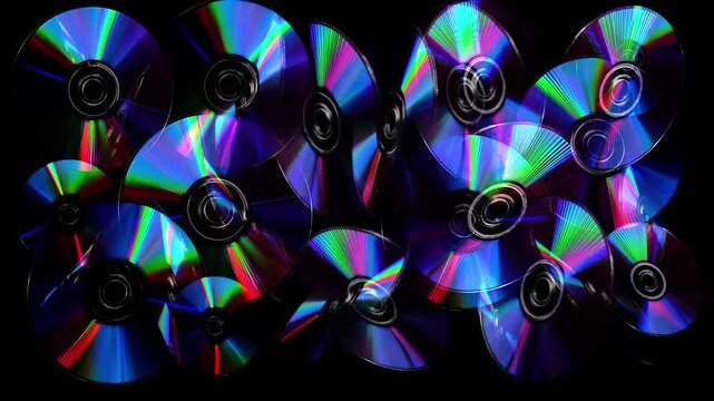 a rotating CD and DVD discs showcasing vibrant rainbow-like colors. Brilliant rainbow diffraction patterns shimmer across the metallic surfaces, creating vivid colors and holographic reflections