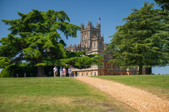 Highclere, United Kingdom - 21.05.2026: Visitors walk on gravel path toward Highclere Castle estate under clear blue sky.