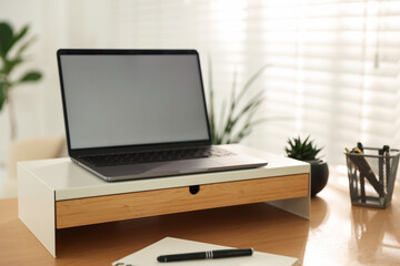 Fototapeta premium Workplace with laptop on riser stand and stationery indoors, closeup