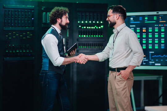 It professionals shaking hands in server room, symbolizing successful partnership, collaboration, and data center agreement