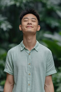 Young man smiling with eyes closed in lush outdoor garden