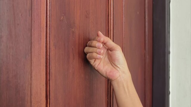 Close up of a woman's hand knocking on a wooden door in 4K, visual only