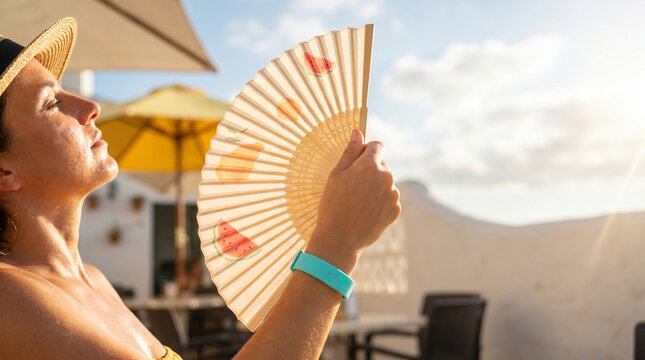 Woman enjoying sunshine while holding a hand fan outdoors  