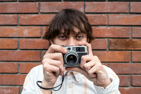 Gen Z retro fashion young man with vintage film camera, hipster analog photography hobby, creative youth culture.