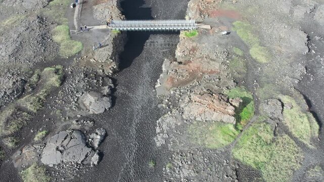 Aerial perspective ascending over the Bridge Between Continents, a symbolic footbridge crossing the rift valley between tectonic plates in Iceland