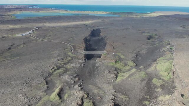 Aerial perspective flying over the Bridge Between Continents, a symbolic footbridge over a major fissure separating two tectonic plates in Iceland