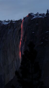 Vertical Screen: Yosemite National Park Firefall phenomenon as sunset light illuminates Horsetail Fall creating a glowing orange lava-like cascade down the granite cliff face