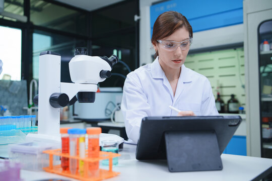 Laboratory Technician Conducting Analysis with Microscope and Tablet