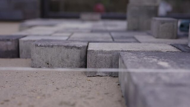 Worker positioning concrete paving block during pavement installation
